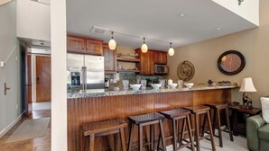 Una cocina moderna con armarios de madera, encimera de granito y taburetes de bar.