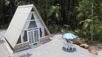 Compact lodging with a glass door and outdoor seating area amidst lush greenery.