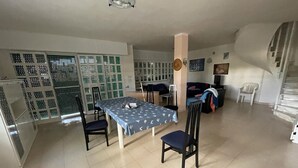 Un vaste espace de vie comprenant une table à manger, des chaises, un canapé et un téléviseur.