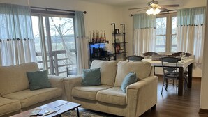 A living room with a sofa, coffee table, and a dining area with a table and chairs. - Trailside Terrace 
Private access to tunnel vision trial (Bella Vista)