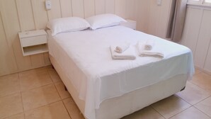 A neatly made bed with white linens and two rolled towels on the bed. - Beautiful and Cozy House Surrounded by Nature (Morretes)