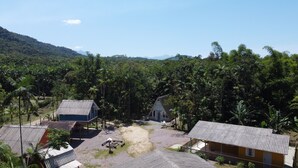 A rural village with several small buildings, including a house with a corrugated metal roof and a wooden structure with a tiled roof. - Beautiful and Cozy House Surrounded by Nature (Morretes)
