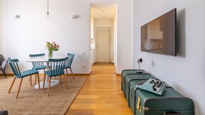 A modern living room with a dining area, a flat-screen TV mounted on the wall, and a wooden floor. - Elegant Apartment with Two Bedrooms (Roma)