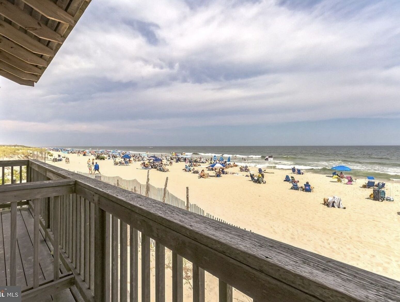A beach with a wooden deck overlooking the sand and ocean.