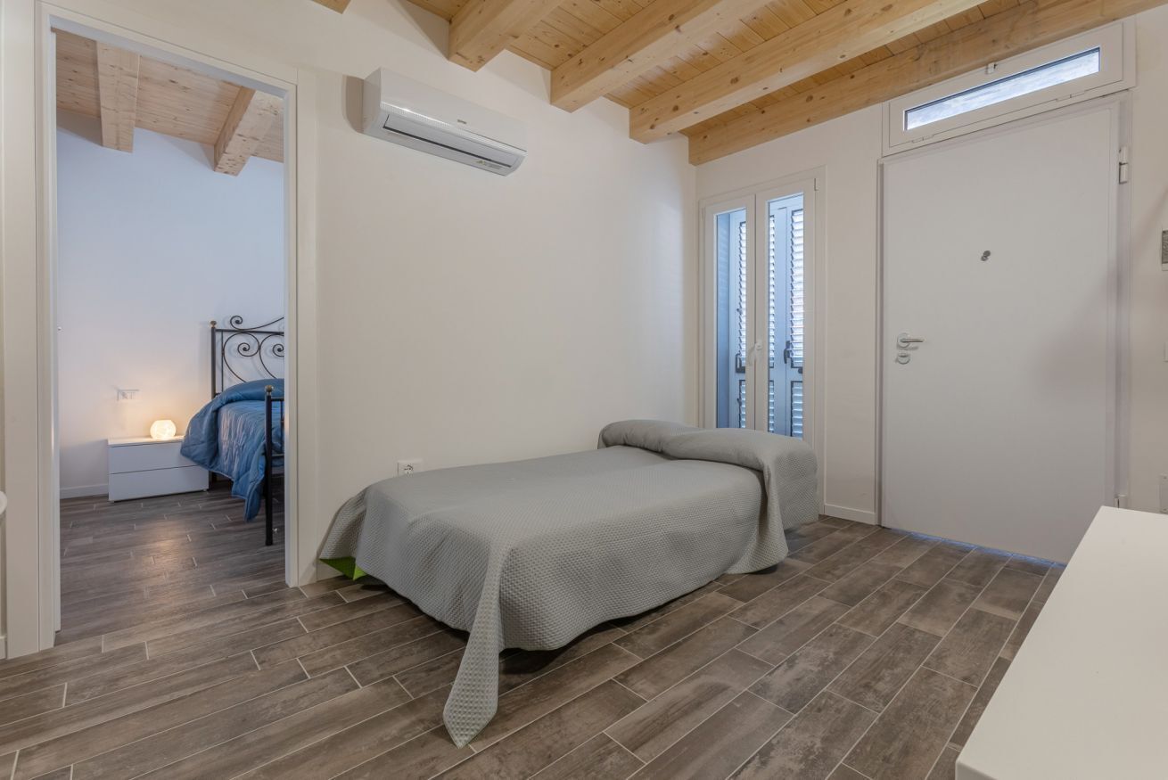 A bedroom with a bed, a nightstand, a window, and a door.