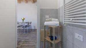 Un baño con un perchero, un estante con toallas y una zona de ducha.