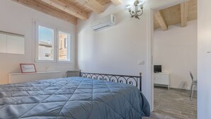 Un dormitorio con cama, unidad de aire acondicionado, escritorio y silla.