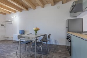A modern kitchen with a dining area, a television, and a flower vase. - GuestHost - Cozy apartment equipped with all comforts to accommodate up to 3 people, including an outdoor patio where you can enjoy pleasant moments of relaxation. The accommodation is located in the Borgo Panigale district, a very quiet residential area (Bologna)