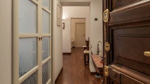 Un couloir avec une porte en bois, un miroir et une petite table avec une chaise.