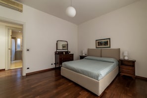 Une chambre à coucher avec un lit, une commode, une table de chevet et un tableau encadré au mur.