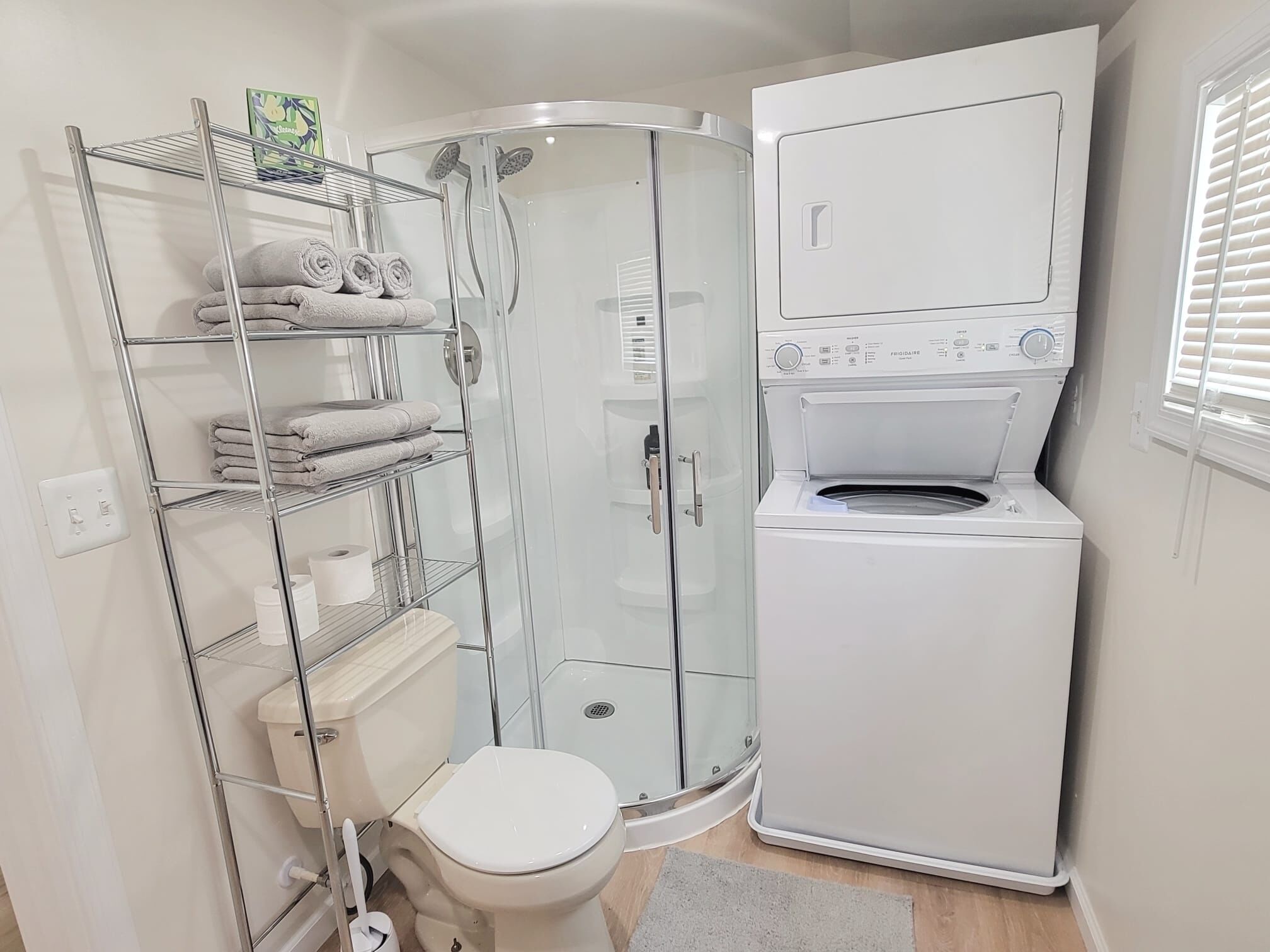 Un baño pequeño con cabina de ducha de vidrio, un inodoro y una lavadora de carga frontal.
