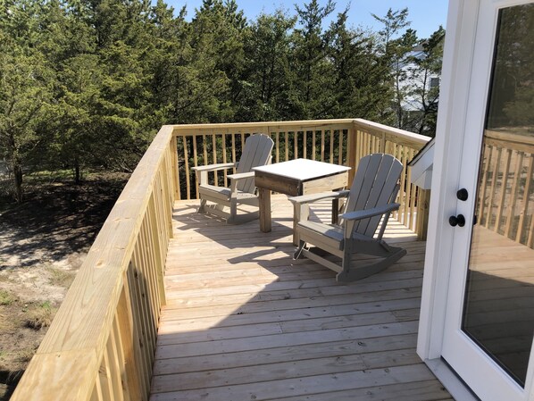 Un pontile in legno con due poltrone Adirondack e un tavolino, immerso tra gli alberi.