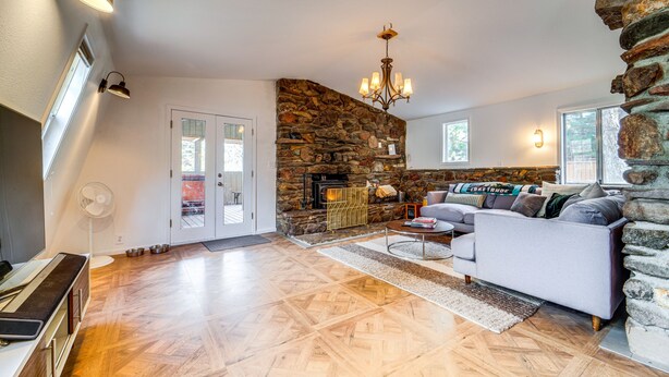 A living room with a stone fireplace, a sofa, and a television. - Near Hiking: Pet-Friendly Sierra Valley Gem (Loyalton)