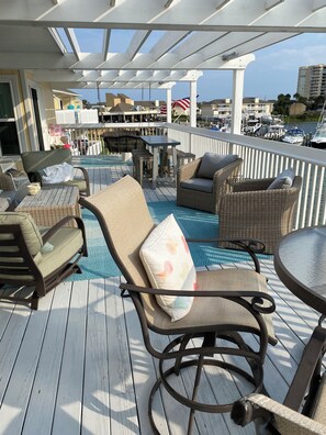 Una terraza con mobiliario de mimbre, mesa de billar y vista al puerto deportivo.