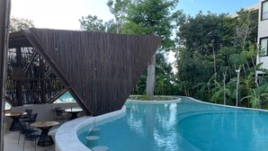A curved pool with a wooden structure and seating area.