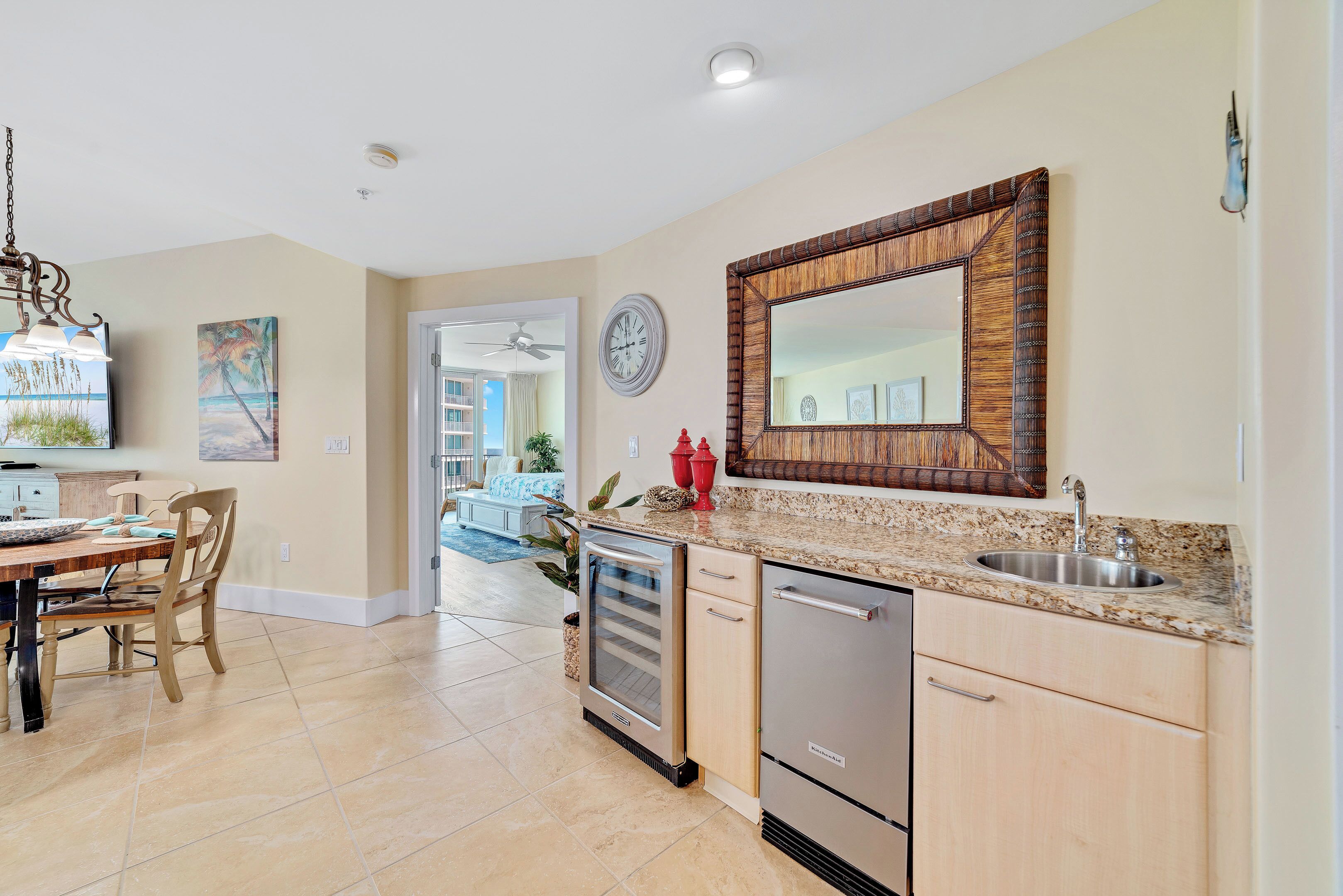 A modern kitchen with a granite countertop, stainless steel appliances, and a large mirror.