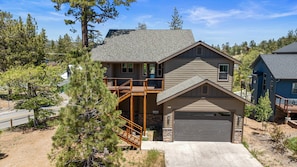 A two-story house with a garage, a balcony, and a stone foundation.