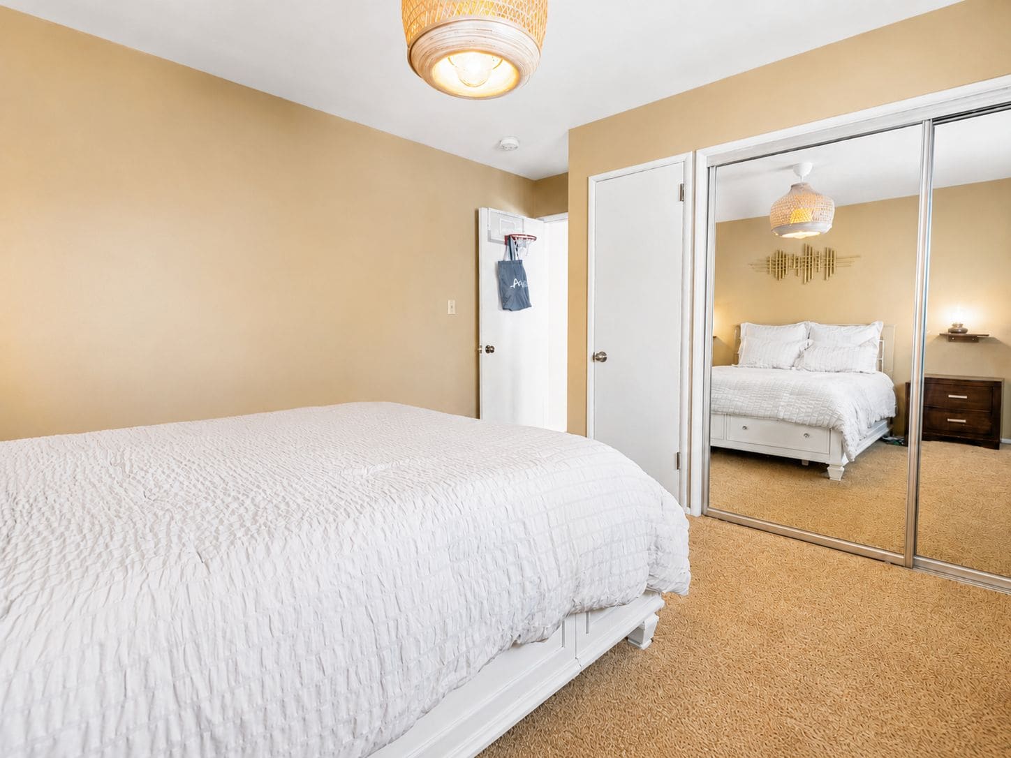 A bedroom with a large bed, a wardrobe, and a mirror reflecting another room.