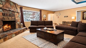 Ein gemütliches Wohnzimmer mit Kamin, braunen Sofas und einem Couchtisch.