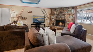 Ein gemütliches Wohnzimmer mit Kamin, bequemen Sofas und einem Fernseher.