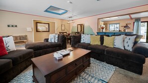 Ein Wohnzimmer mit zwei Sofas, einem Couchtisch und einem Essbereich mit Tisch und Stühlen.