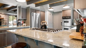 A modern kitchen with granite countertops, stainless steel appliances, and wooden accents. - Evergreen - Luxury 3BR | En-Suite, Hot Tub, Game Room (Big Bear Lake)