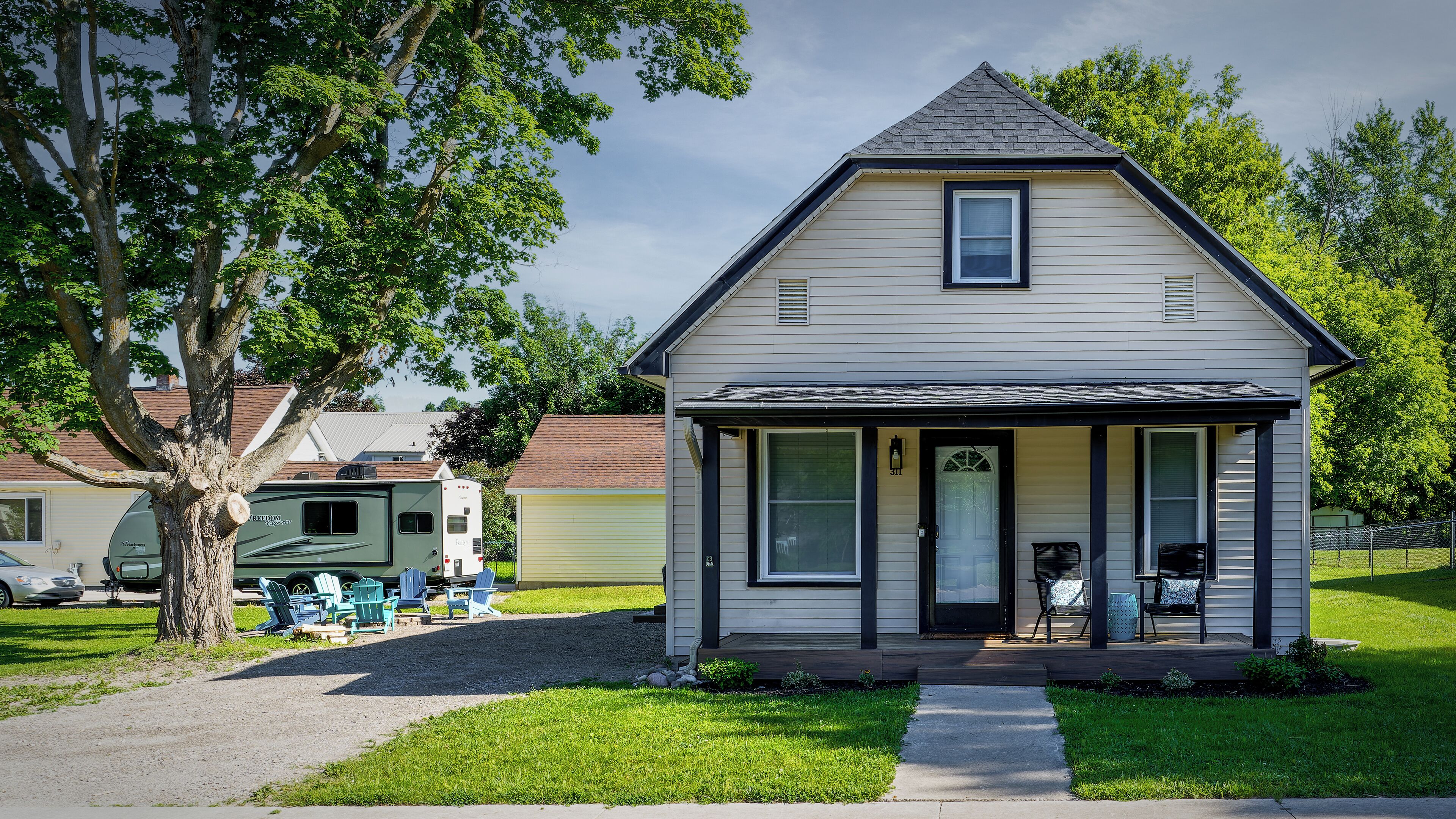 A small, single-story house with a front porch, a visible mailbox, and a clear sky.