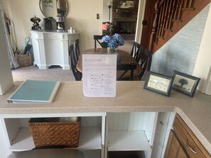 Una mesa de recepción con un cartel de bienvenida, cuadros enmarcados y un menú.