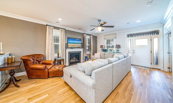 A spacious living room with a fireplace, leather armchair, and a large grey sofa. - Rooftop Deck, Ocean Views & Elevator: Huge Home 6BR/4.5BA.  Steps from beach! (Ocean City)