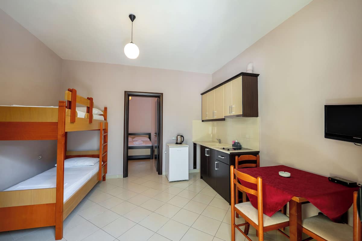 A compact room with bunk beds, a kitchenette, a dining area, and a TV.