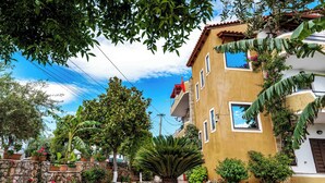 A yellow building with a stone wall and potted plants. - Flower Garden Villa (Ksamil)