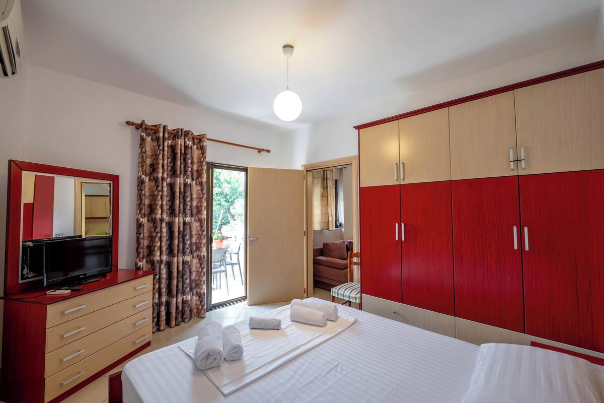 A hotel room with a bed, a TV, a wardrobe, and a bathroom visible through an open door.