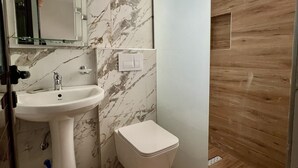 A bathroom with a marble sink, a toilet, and a wooden vanity. - Flower Garden Villa (Ksamil)