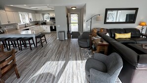 Een moderne keuken met witte kasten, een centraal eiland en een eetgedeelte met houten stoelen.
