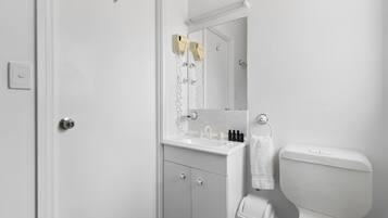 Baño con lavamanos blanco, espejo y retrete.