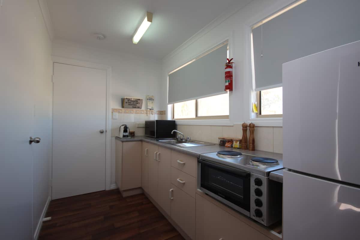 A compact kitchen with a refrigerator, microwave, oven, and sink.