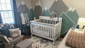 A baby room with a crib, rocking chair, and a mountain-themed wall. - LU Commencement Rental - Easy 15 minute drive to LU campus. (Forest)