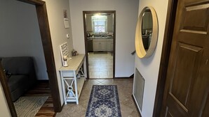 A hallway with a blue patterned rug, a wooden door, a mirror, and a ceiling light fixture. - LU Commencement Rental - Easy 15 minute drive to LU campus. (Forest)