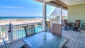 Un espace extérieur abrité avec une piscine, des chaises et une vue sur la plage.