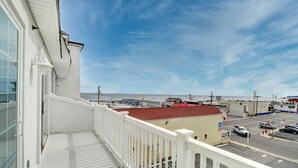 Een balkon met uitzicht op het strand en een parkeerplaats.