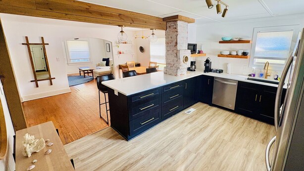 Een moderne keuken met een centraal eiland, donkere kastjes en een houten plafond.