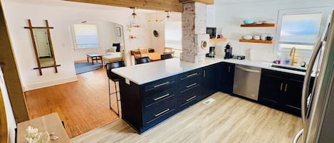 A modern kitchen with a central island, dark cabinetry, and a wooden ceiling.