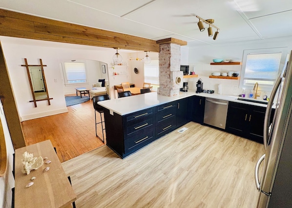 Een moderne keuken met een centraal eiland, donkere kastjes en een houten plafond.
