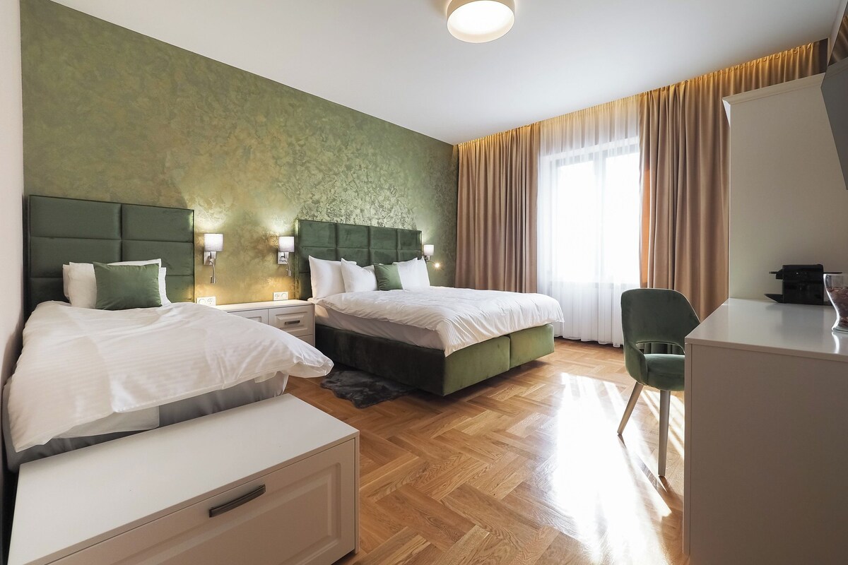 A hotel room with two beds, a desk, and a chair.