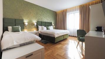 A hotel room with two beds, a desk, and a chair.