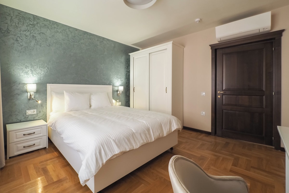 A bedroom with a bed, bedside tables, a wardrobe, and a chair.