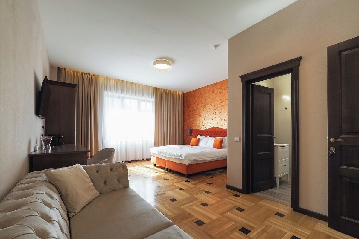 Una habitación de hotel con una cama, un sofá, un escritorio y una televisión.