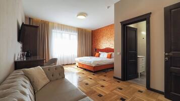 Ein Hotelzimmer mit Bett, Sofa, Schreibtisch und Fernseher.
