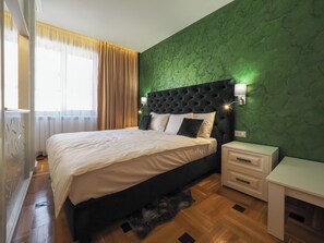 A bedroom with a bed, bedside tables, a nightstand, a green textured wall, and a window with curtains. - Boutique Central Sibiu (Sibiu)