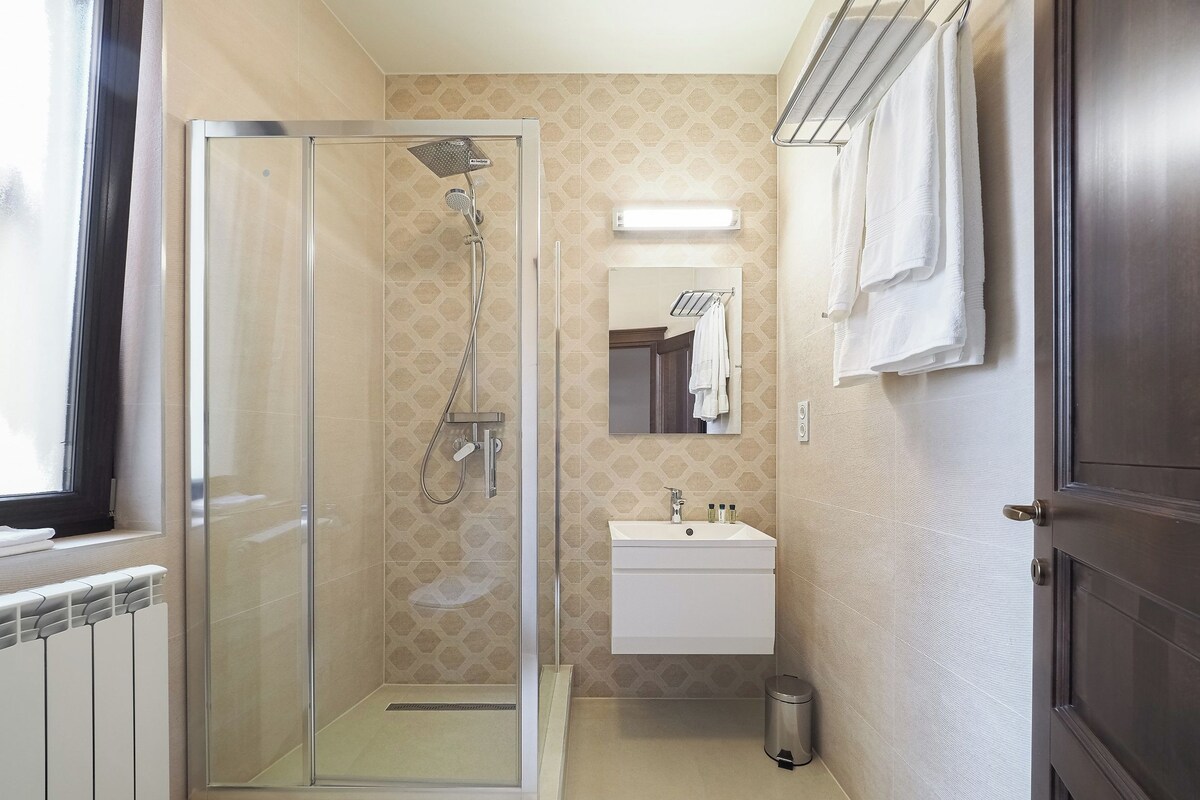 A modern bathroom with a glass-enclosed shower, a sink, and a mirror.